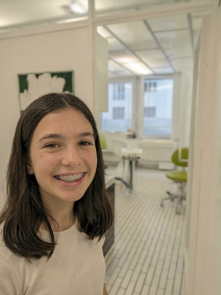 Mädchen mit fester Zahnspange lächelt in der Praxis ZugSmile in Zug